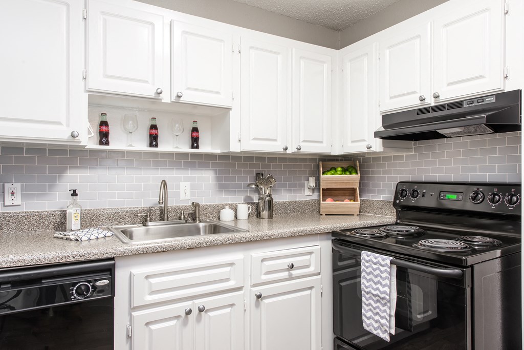 Pet-Friendly Apartments in Sandy Springs – Celebration at Sandy Springs - a kitchen with white cabinets and black appliances