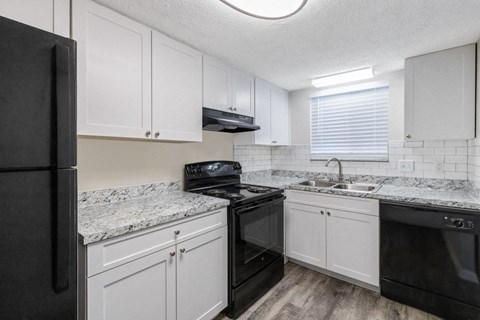 an empty kitchen with white cabinets and black appliances
