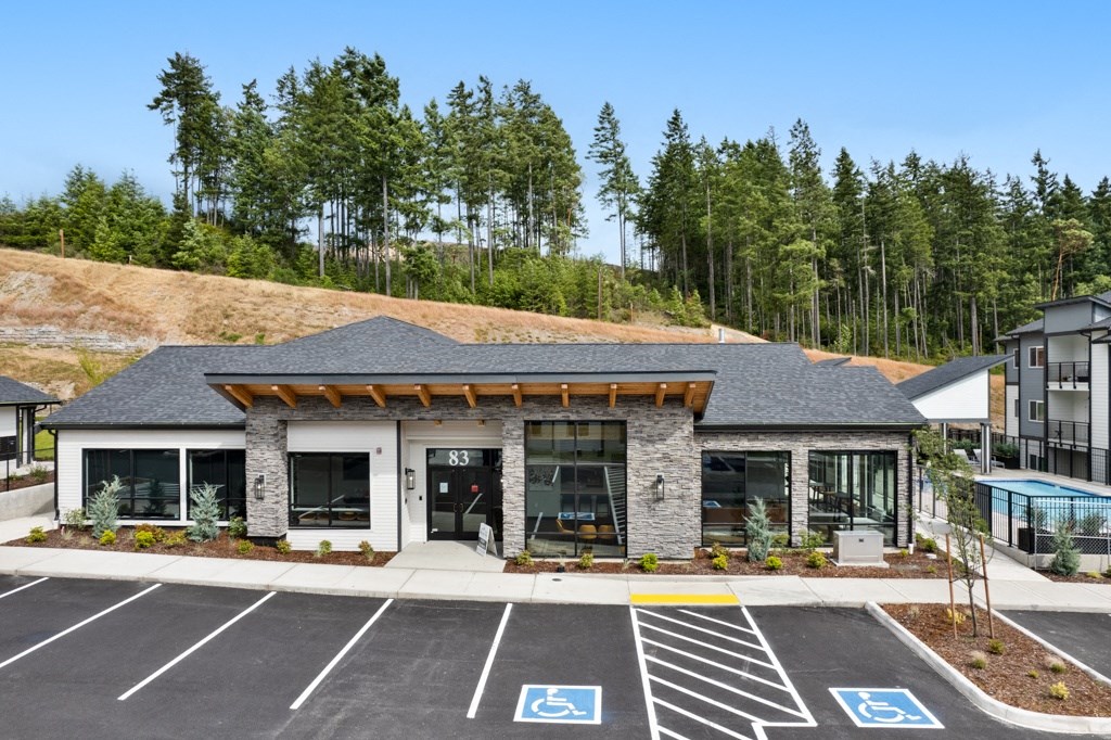a building with a parking lot and trees in the background,