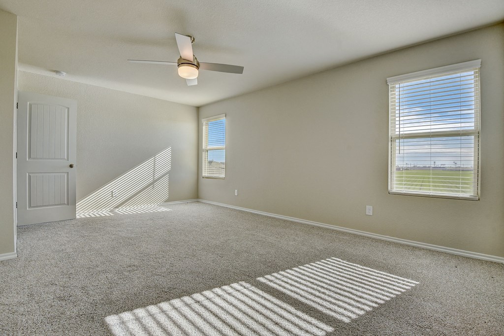 an empty living room with carpet and a ceiling fan