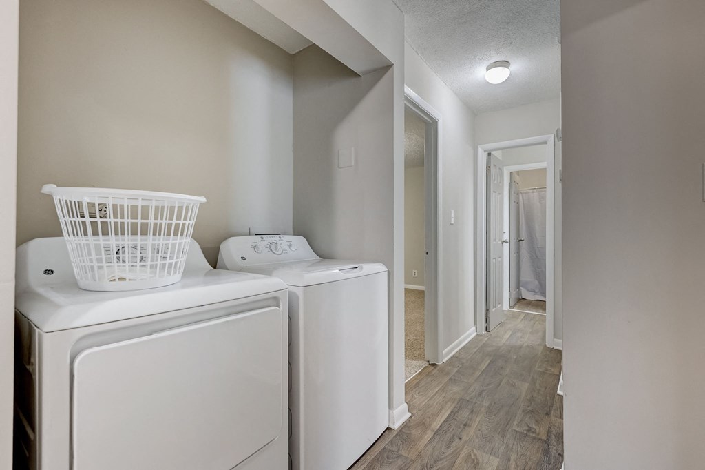 Pet-Friendly Apartments in Sandy Springs – Celebration at Sandy Springs - a washer and dryer in a laundry room with a hallway and a door