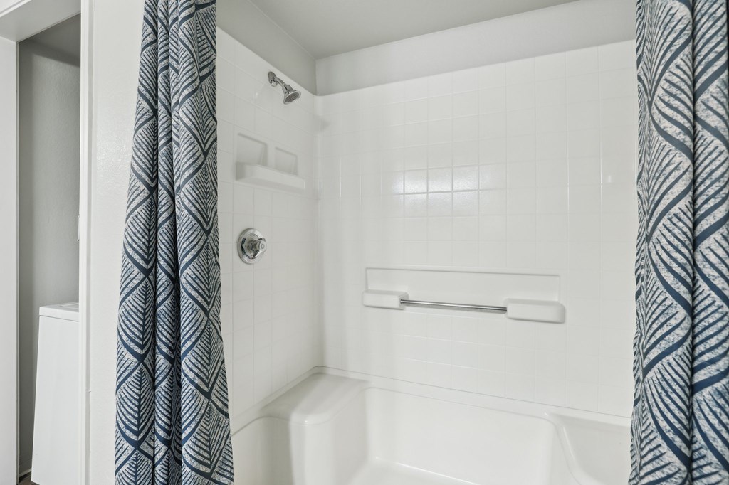 A white bathtub with a shower curtain on the side.