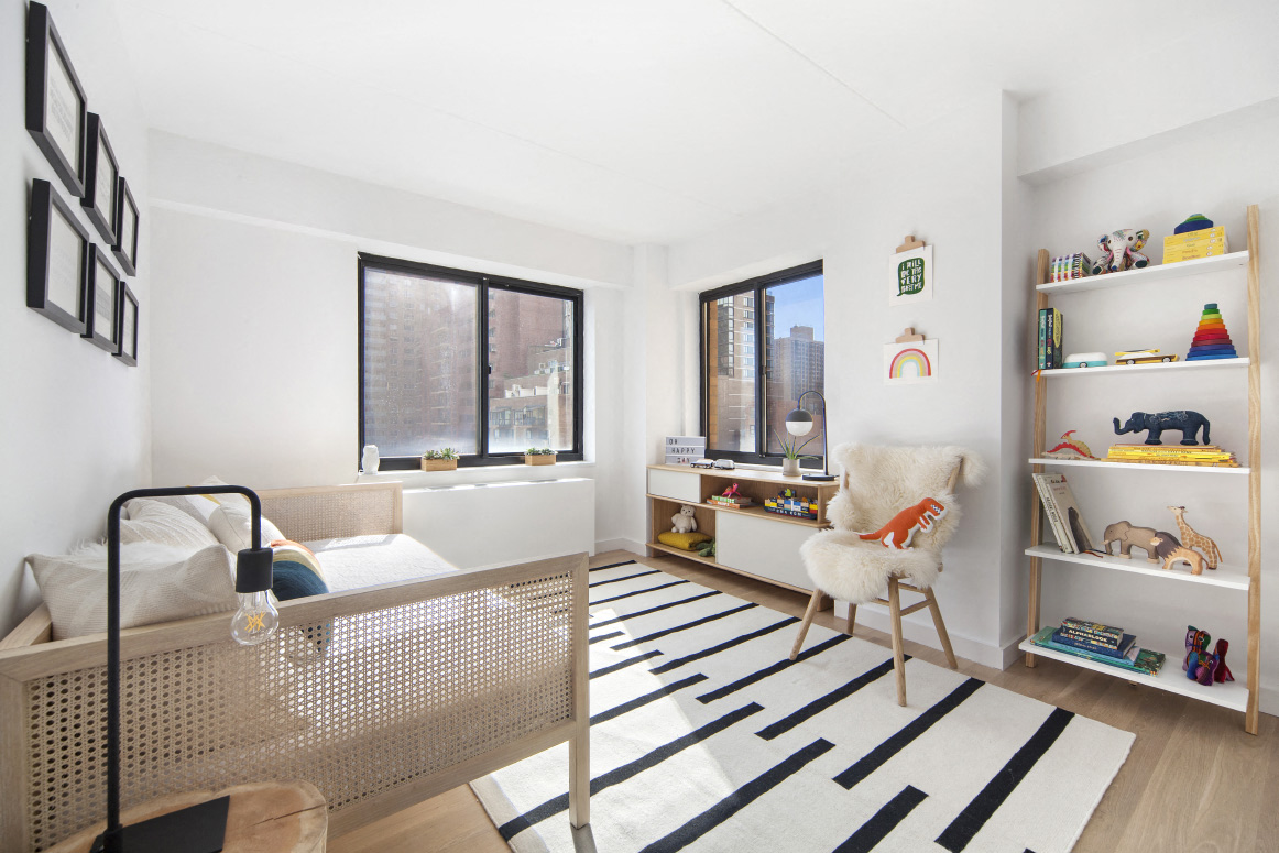 a living room with a bed and a rug in front of a window
