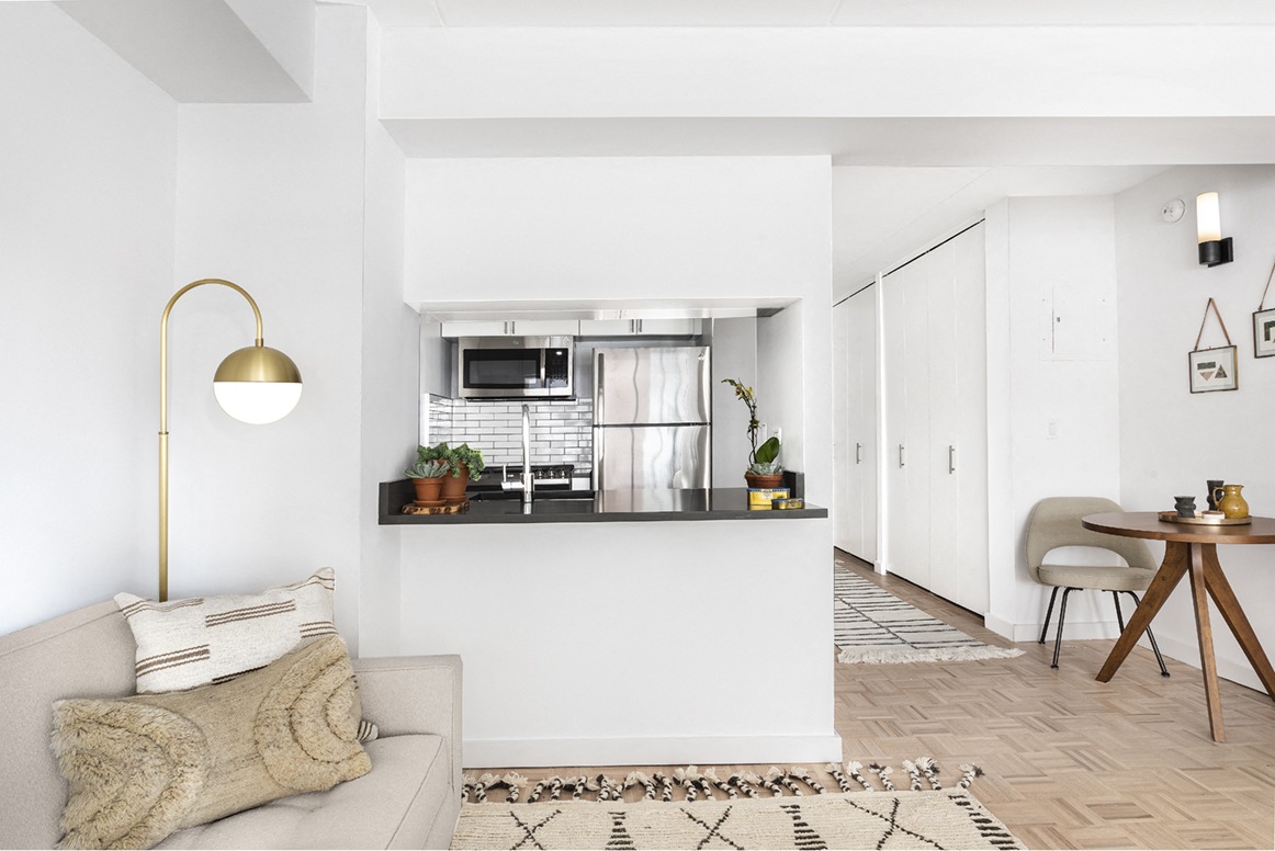 a living room with a couch and a kitchen with a counter