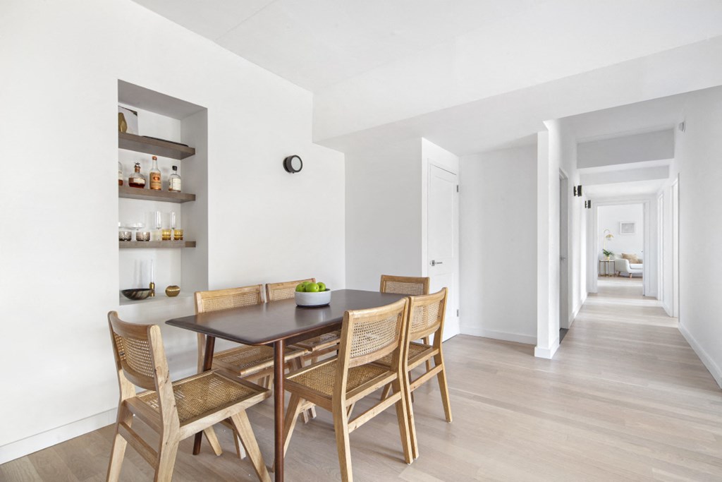 a dining room with white walls and a wooden table and chairs