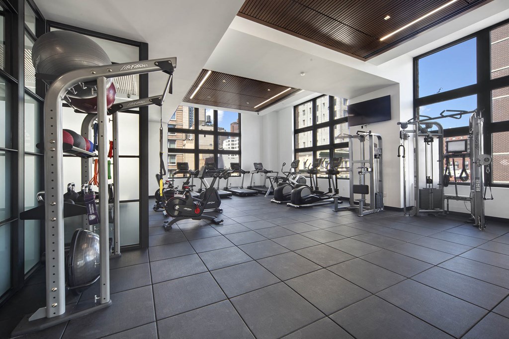 a gym with weights and cardio equipment and windows