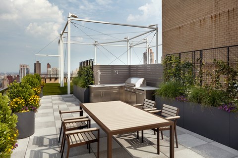 a terrace with a table and chairs and a grill on a roof