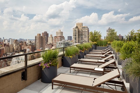 a rooftop patio with tables and benches and a view of the city
