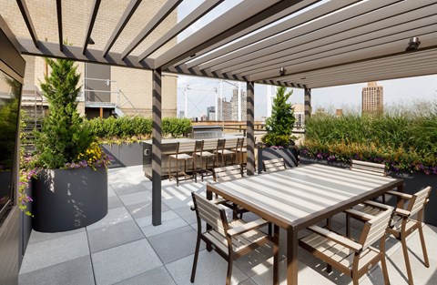 the terrace of a building with a wooden table and chairs