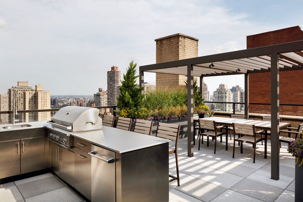 a rooftop barbecue area with a city in the background and a table with chairs