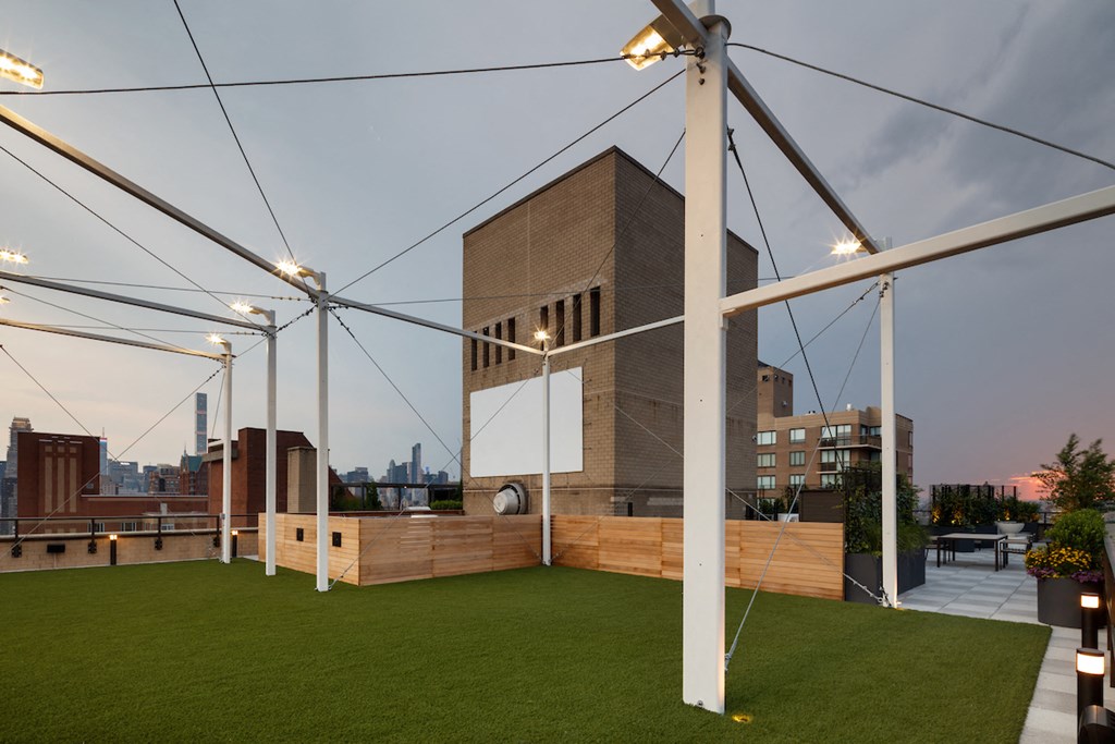 a roof garden with grass and a building in the background