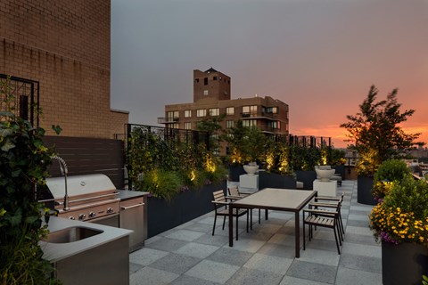 a roof terrace with a table and chairs and a building in the background