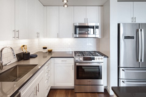 Apartments for Rent in Upper East Side - Bright Premium Kitchen with Stainless Steel Appliances, White Cabinets, and Sleek Tiled Backsplash