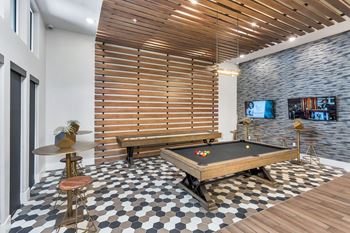 A room with a pool table and a bar stool.