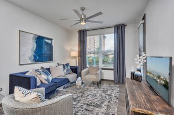 A living room with a blue couch and a ceiling fan.