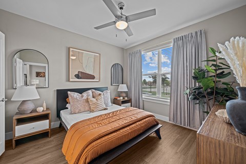 A bedroom with a bed, nightstand, and a ceiling fan.