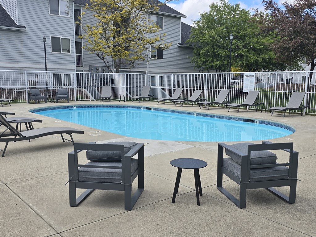 a swimming pool with chairs and tables around it