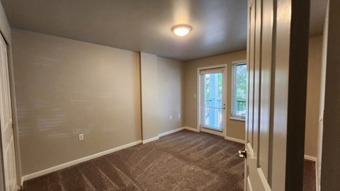 A room with a carpeted floor and a window with blinds.