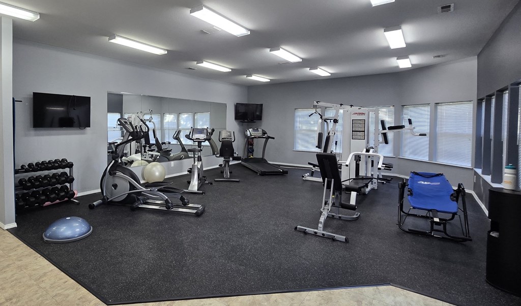 a gym with cardio equipment and a tv in a building
