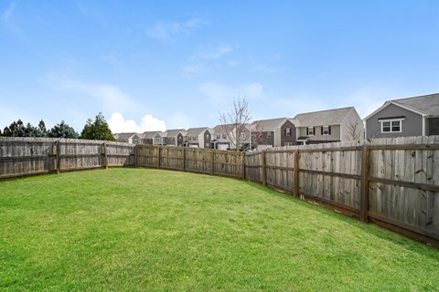 A backyard with a wooden fence and a green lawn.