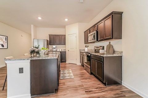 A kitchen with dark brown cabinets and a black refrigerator.