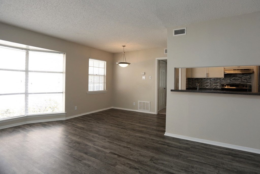 an empty living room and kitchen with a large window