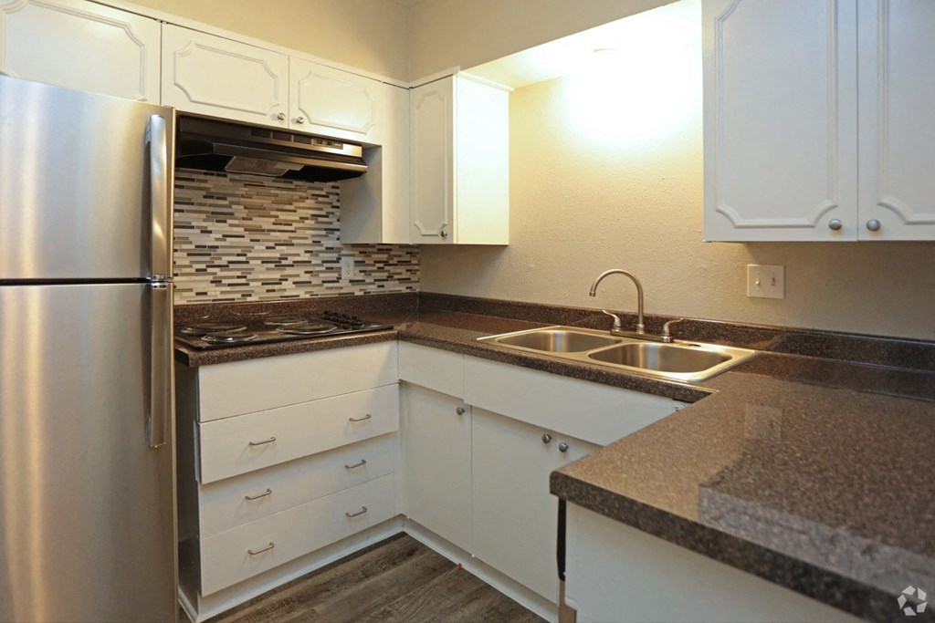 a kitchen with white cabinets and a sink and a refrigerator