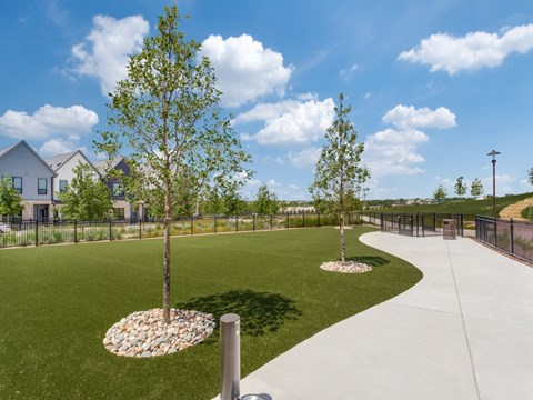 A park with a paved walkway, grassy areas, and trees.
