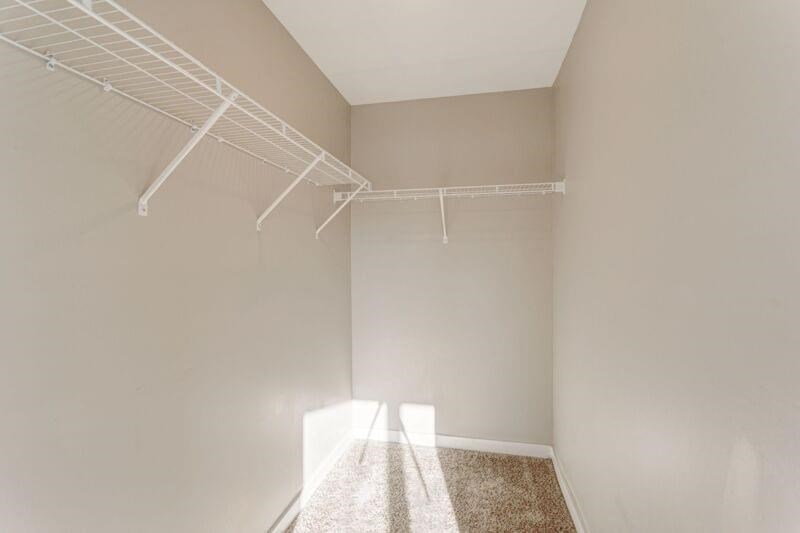 an empty white closet with white rods on the walls