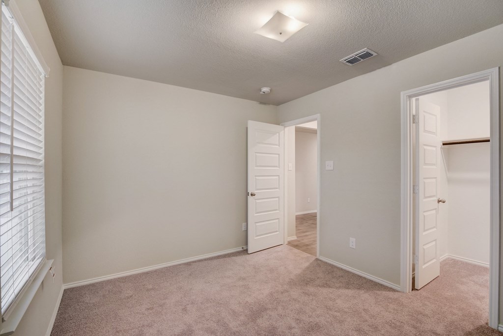 an empty bedroom with a closet and a door to a bathroom