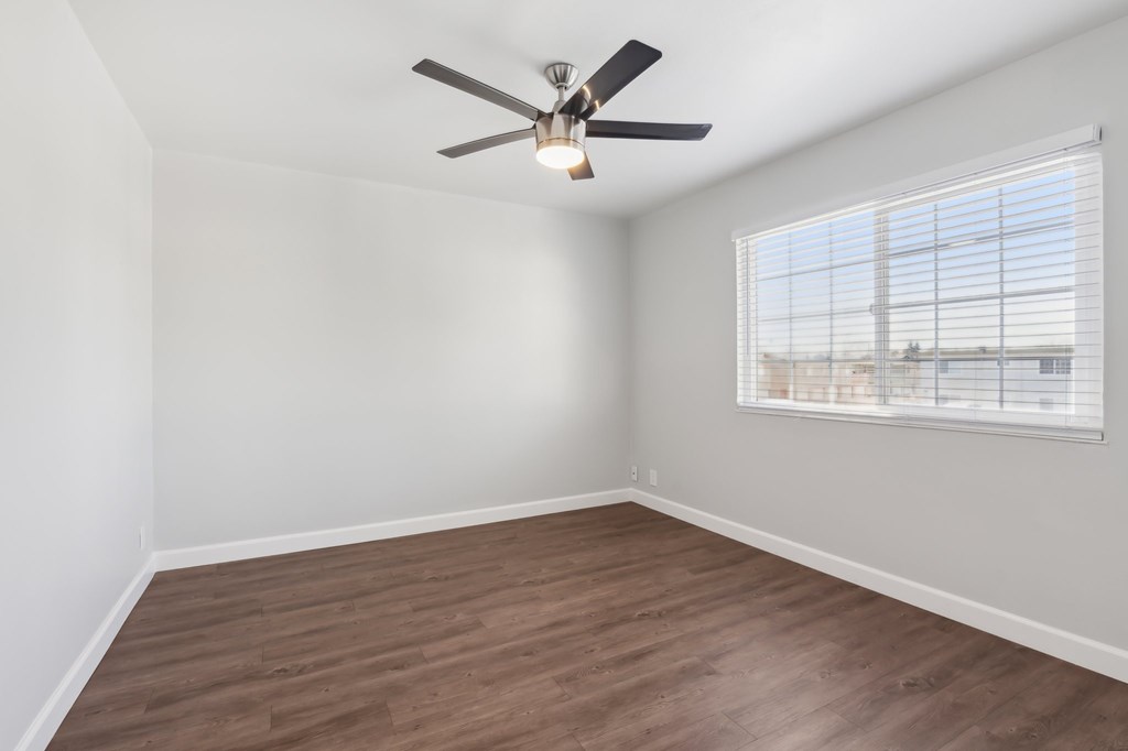 A room with a ceiling fan and a window with blinds.