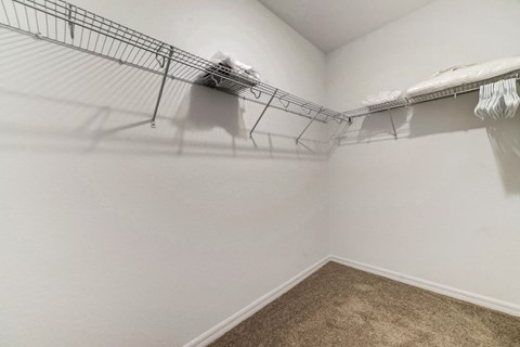 Empty walk-in closet with wire shelving, hangers, and bagged items.