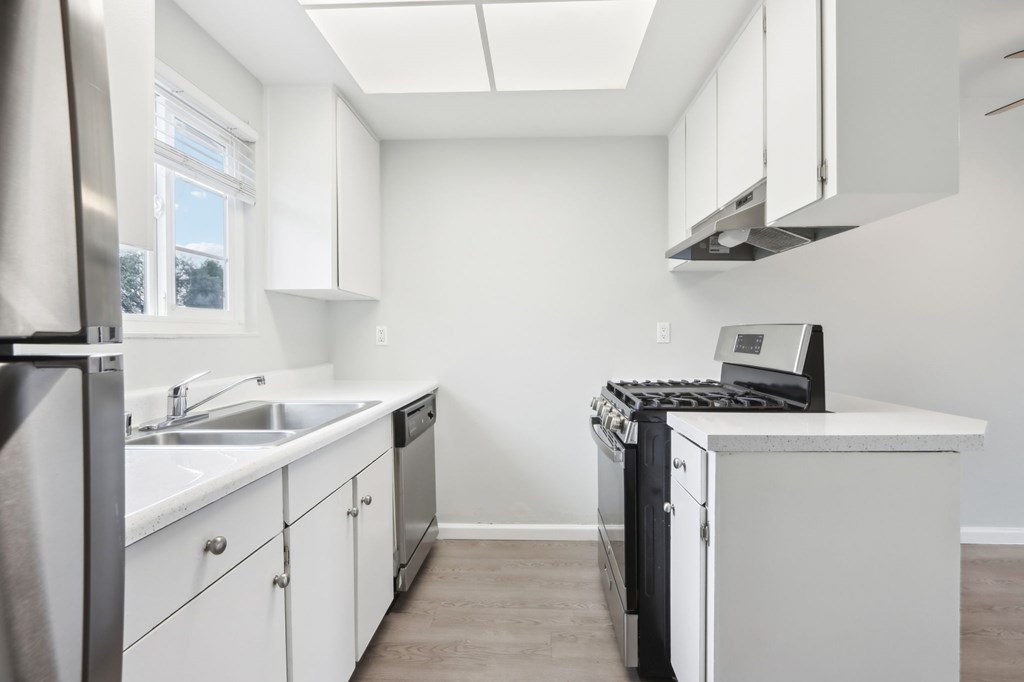 A modern kitchen with white cabinets and a black dishwasher.