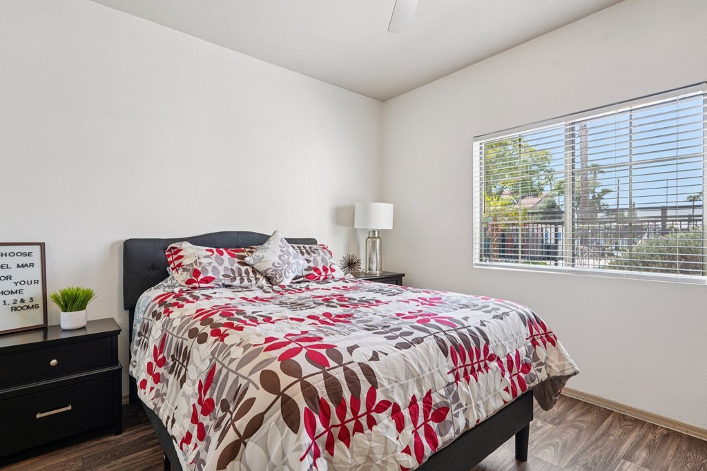 A bedroom with a bed, nightstand, and window.