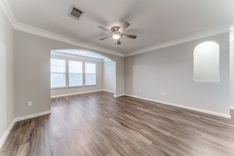 Apartments in San Antonio, TX for Rent - Club at Stone Oak - Unfurnished Living Room Space with Hardwood Floors, a Ceiling Fan, Grey Walls, Alcove, Windows, and a Spacious Layout