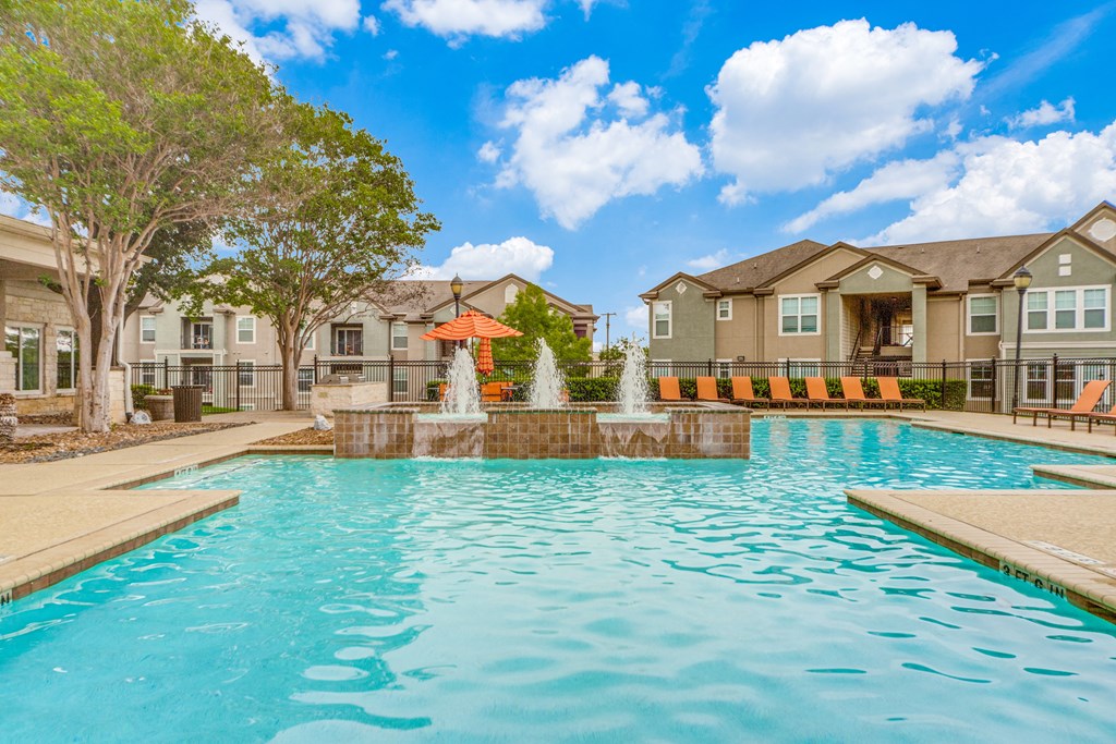 San Antonio, TX Apartments - Club at Stone Oak - Resort-Style Pool with Water Feature, Lounge Chairs, Umbrellas, and Beautiful Landscaping
