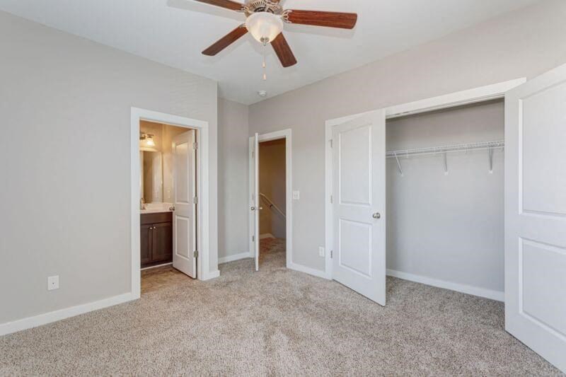 a bedroom with a ceiling fan and a closet