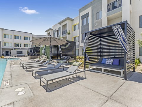 A sunny day at the poolside with lounge chairs and umbrellas.