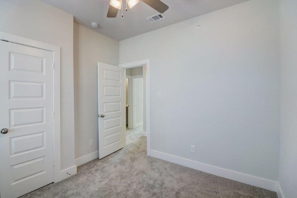 an empty bedroom with white doors and a carpeted floor