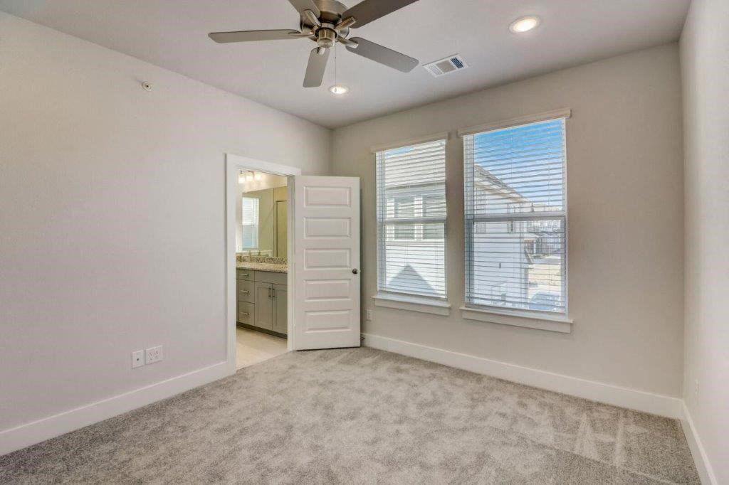 an empty living room with a ceiling fan and a window