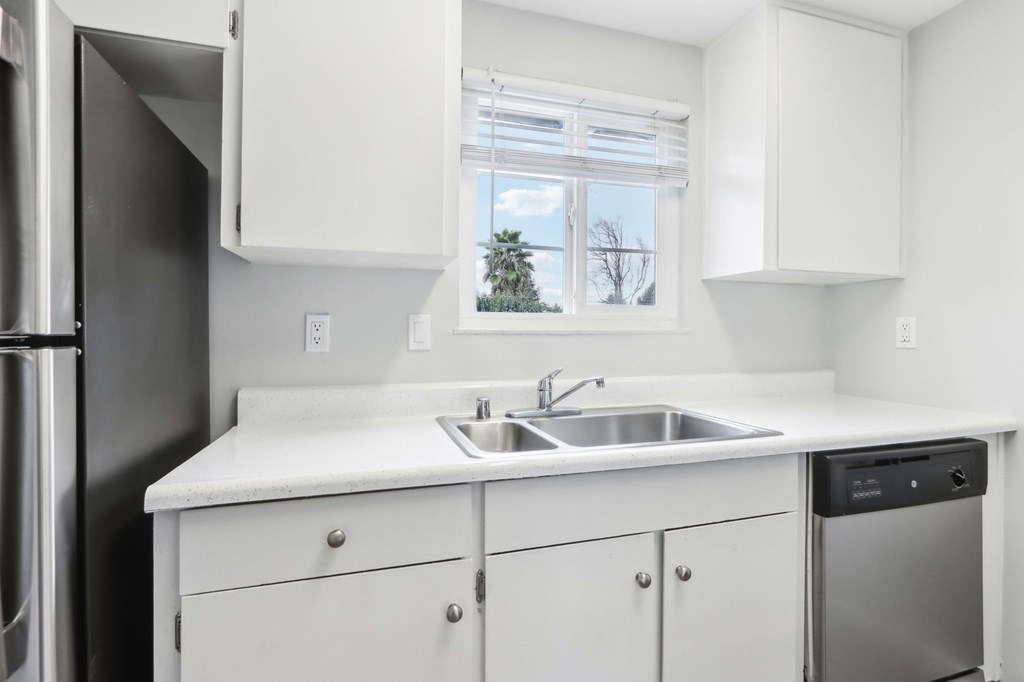 A kitchen with white cabinets and a window.