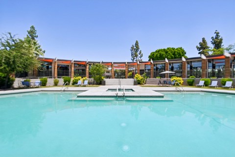 A large swimming pool in front of a building with a clear blue sky.