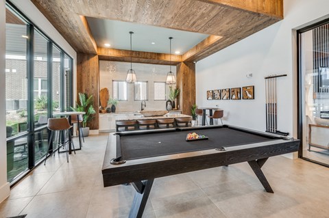 A pool table is in the middle of a room with a wooden ceiling.