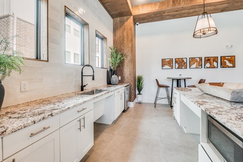 A kitchen with white cabinets and a marble countertop.