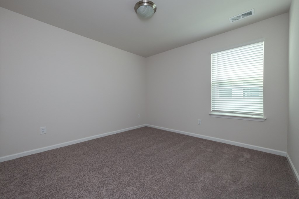 an empty room with a window and carpet