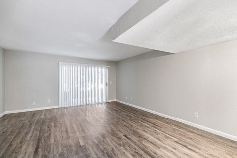 an empty living room with wood flooring and a window