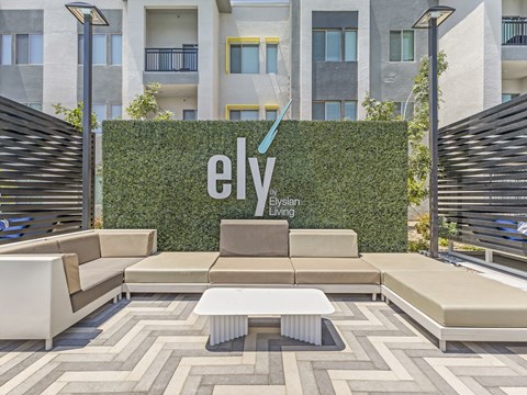 A modern outdoor seating area with a green wall and Ely Living sign.