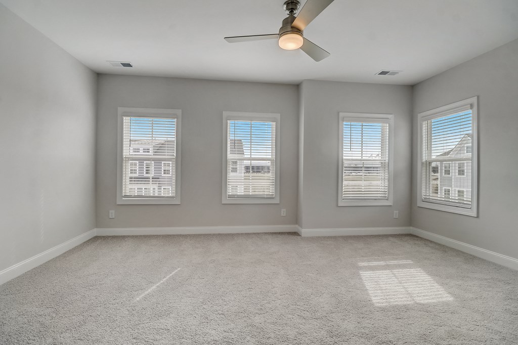 an empty room with a ceiling fan and three windows