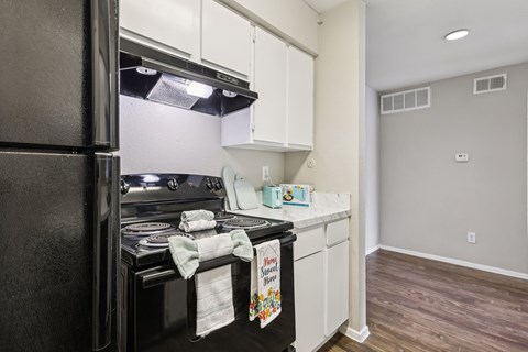 A kitchen with a black refrigerator and white cabinets.