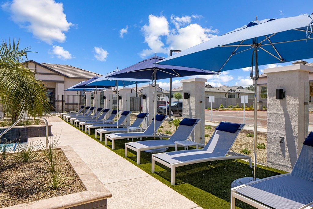 A row of white lounge chairs are arranged on a patio.